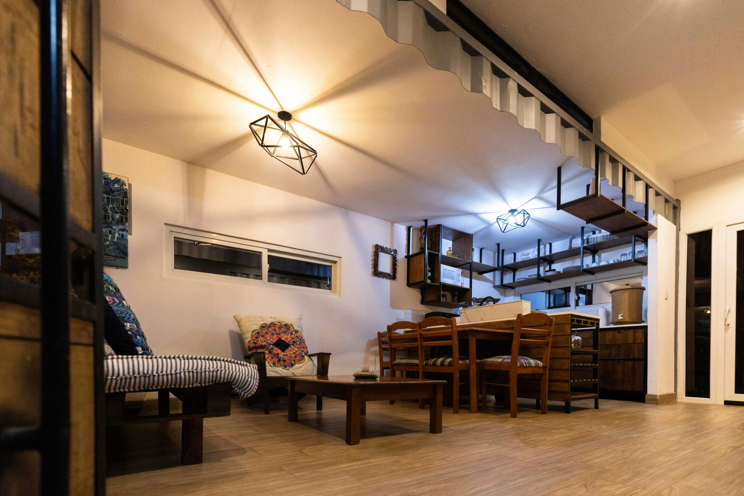 Stylish and inviting modern dining and living room interior with wooden furniture and geometric lighting.